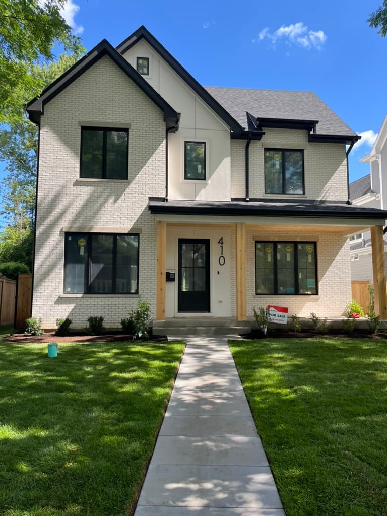 Full front facade showcasing white brick exterior with contemporary black window frames and covered front porch