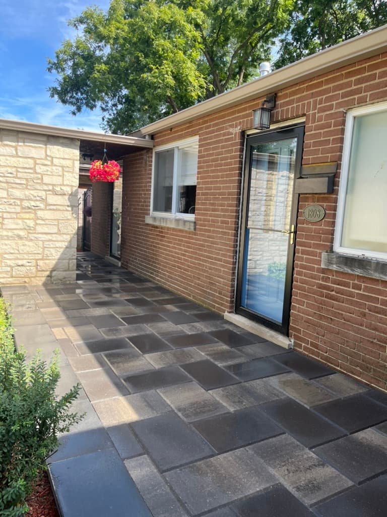Multi-toned paver walkway with random pattern alongside brick ranch home