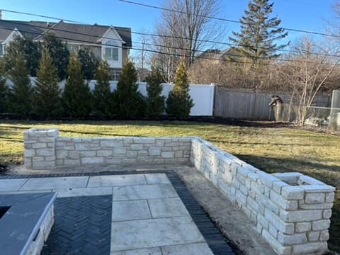 Natural limestone seating wall taking shape with paver patio foundation
