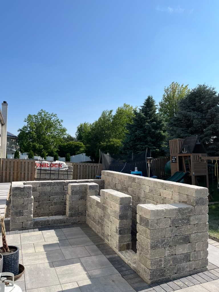 Tumbled stone seating wall construction with Unilock paver patio