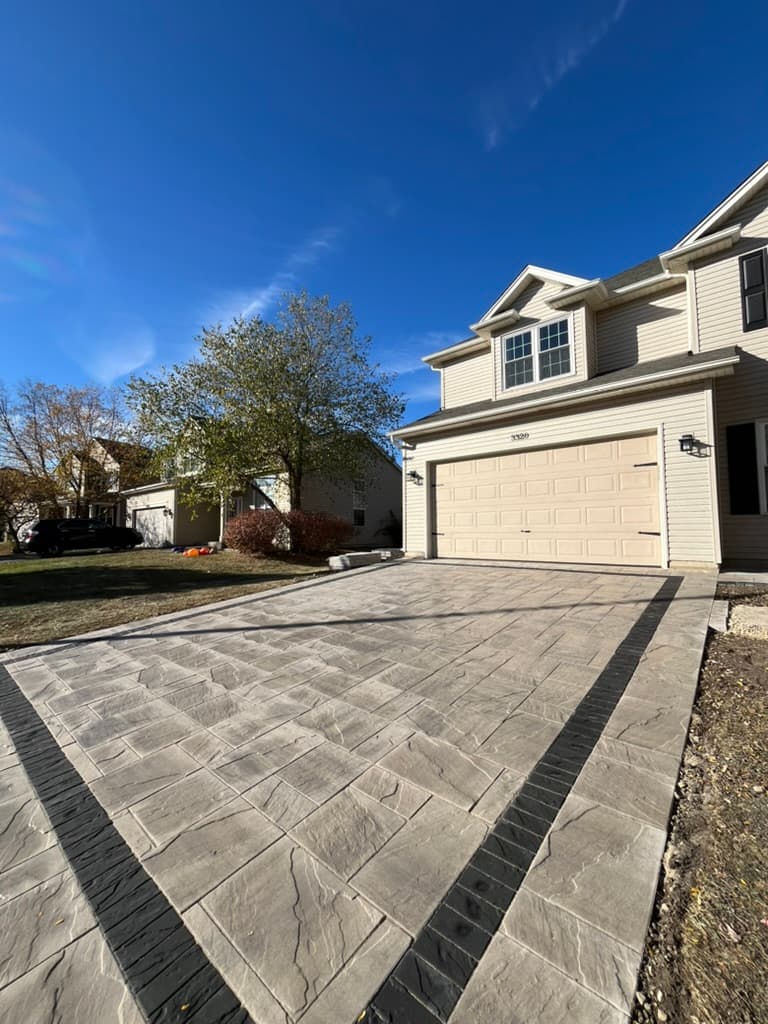 Interlocking paver driveway with dark border accent extending to garage