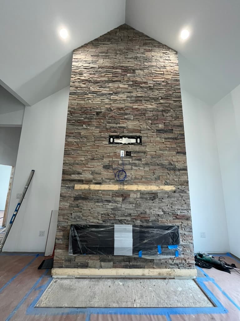 Dramatic floor-to-vaulted-ceiling stacked stone fireplace with TV mount integration