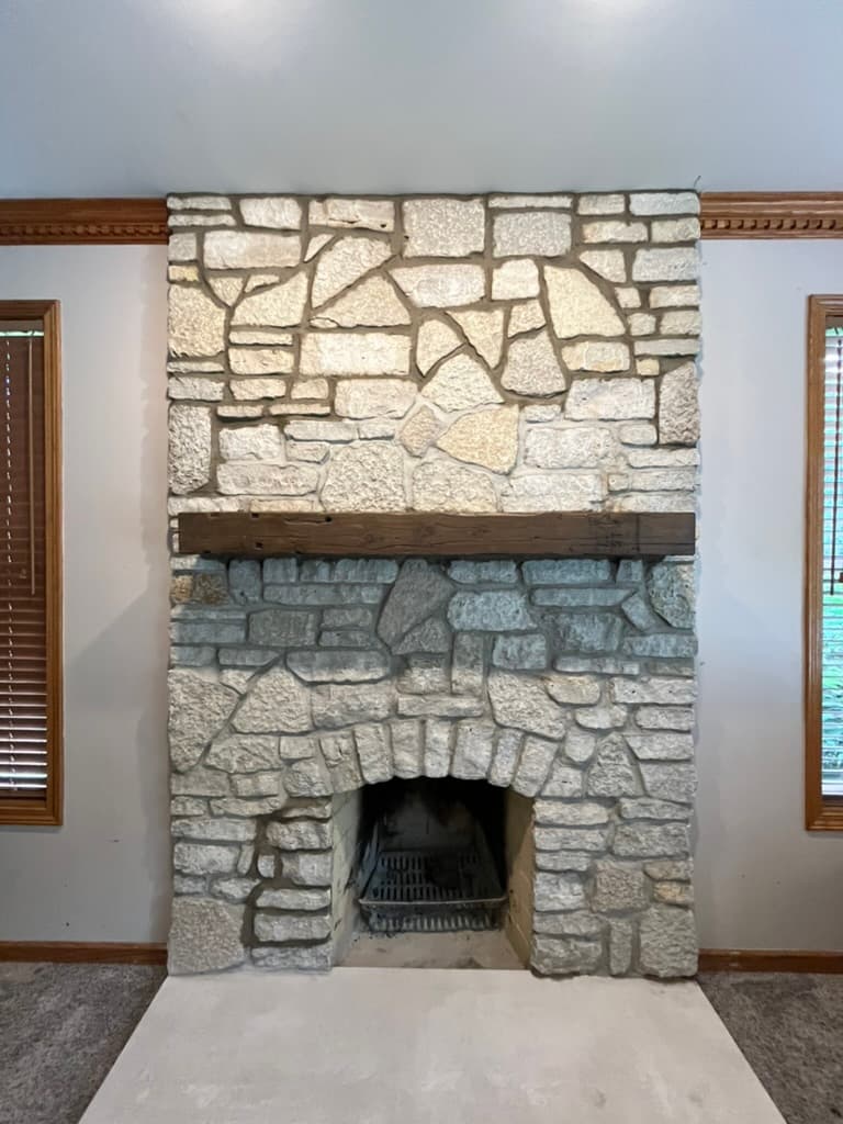 Rustic natural stone fireplace with reclaimed wood mantel and traditional arch