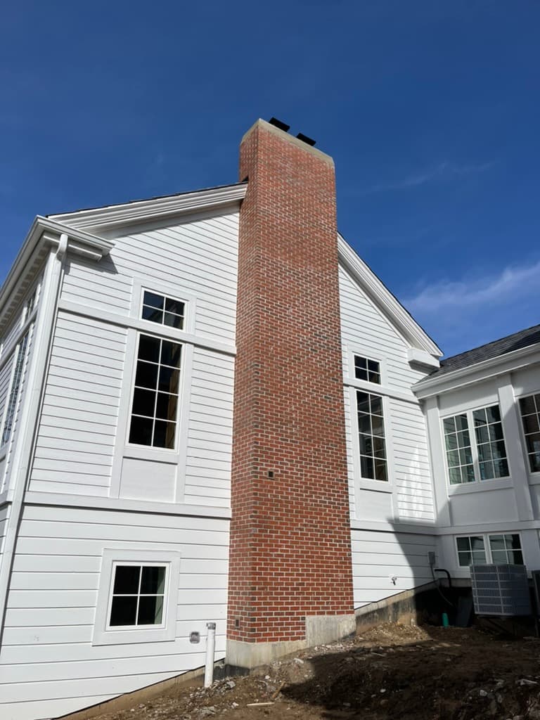 Classic red brick chimney rising along the exterior of colonial home
