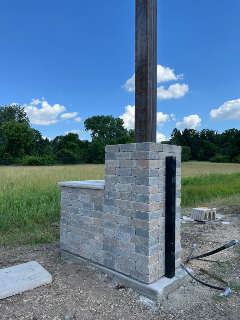 Custom tumbled stone mailbox enclosure at rural property entrance